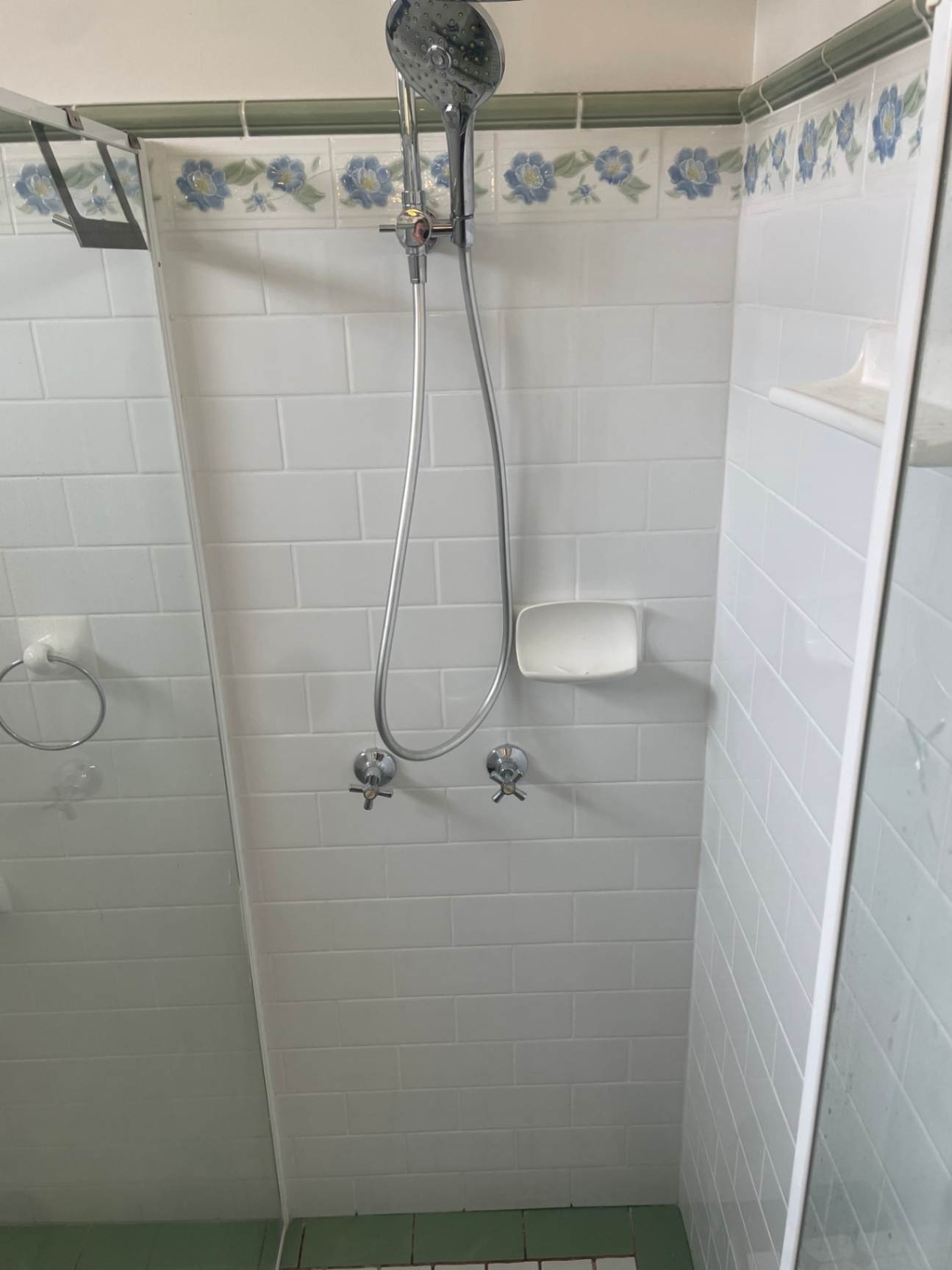 White tiled shower with floral border trim.