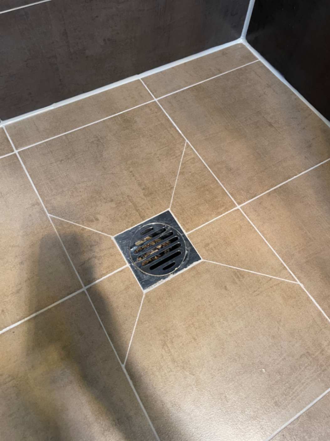 Beige tiled shower floor with centered drain.