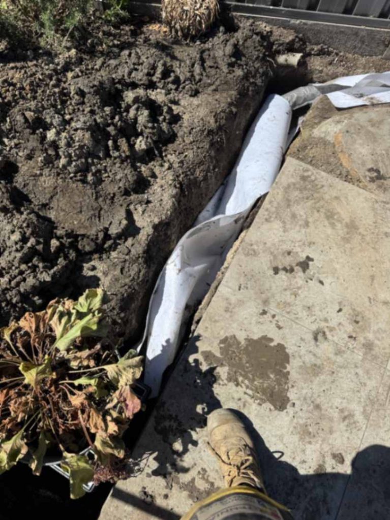 Drainage trench with white pipe installation.