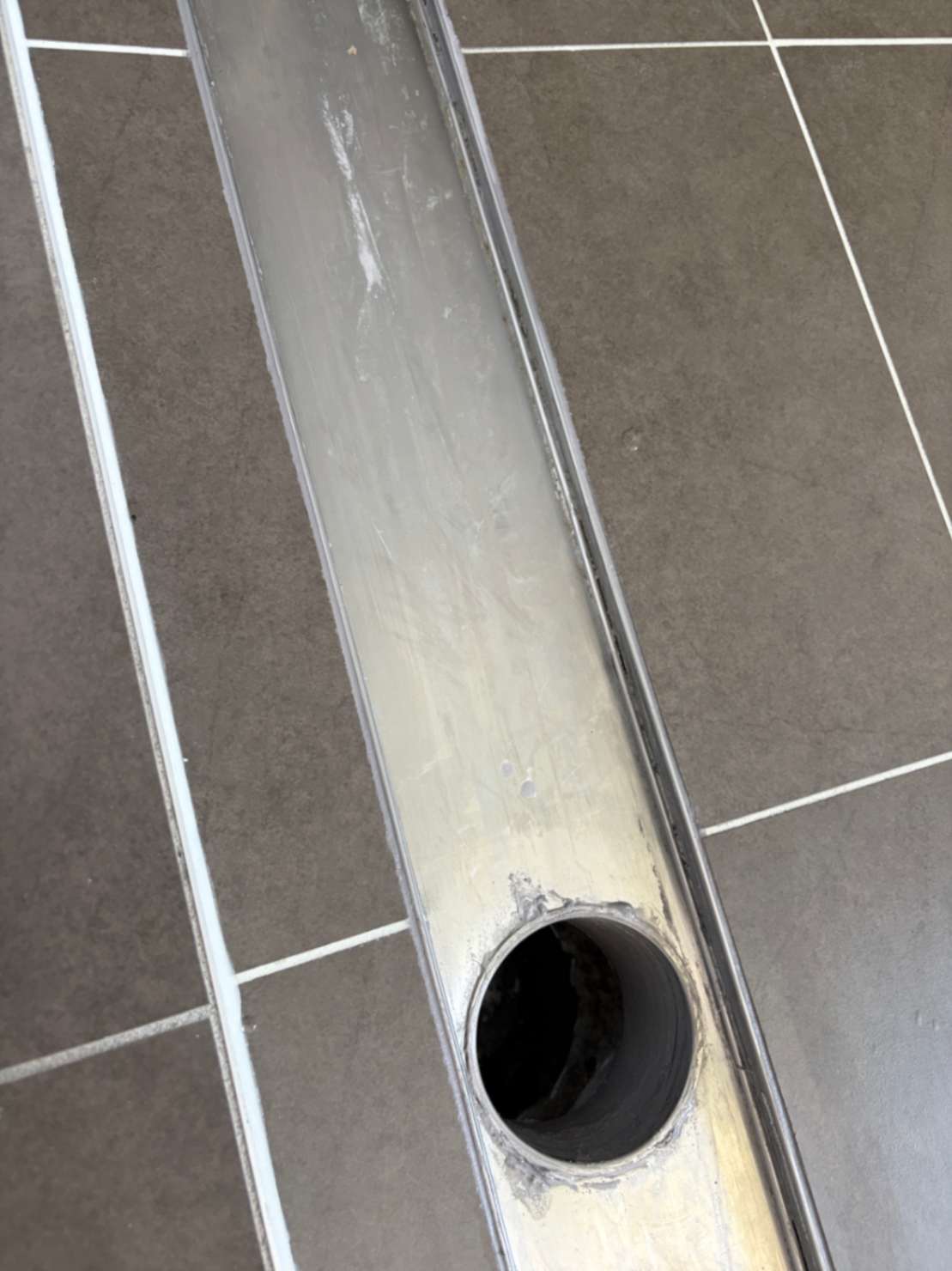 Worn grout and sealant on shower base before repairs