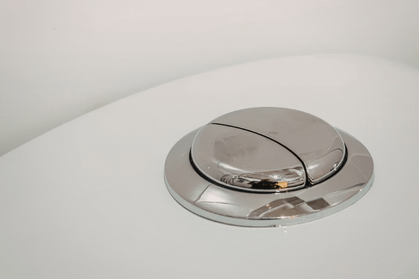 Chrome dual-flush button on a white cistern, a common point of weak or inconsistent flushes