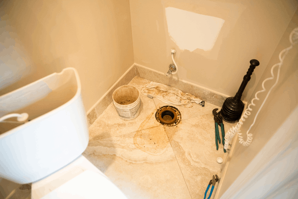 Toilet base lifted with floor flange exposed during a base leak repair